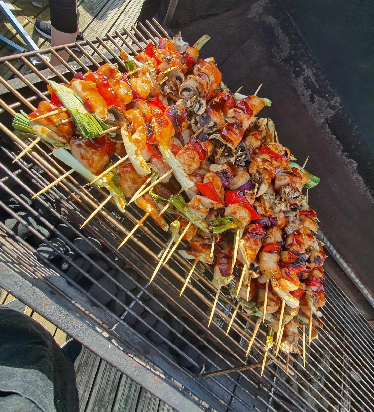 Grillspyd med kylling og peberfrugt på række over kullene